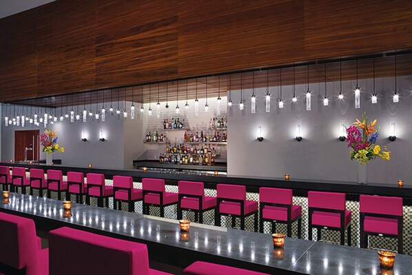 A bar area with a long counter, multiple chairs, and hanging lights. - Secrets Riviera Cancún All Preferred - Adults Only - All inclusive (Puerto Morelos)