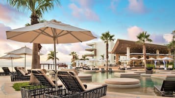 Una piscina al aire libre, sombrillas, sillones reclinables de piscina