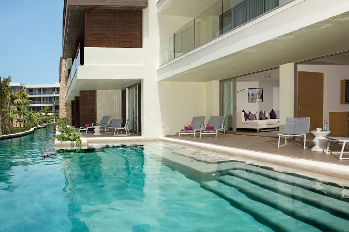 Un hôtel moderne doté d’une piscine, de chaises longues et d’un bâtiment à deux étages.