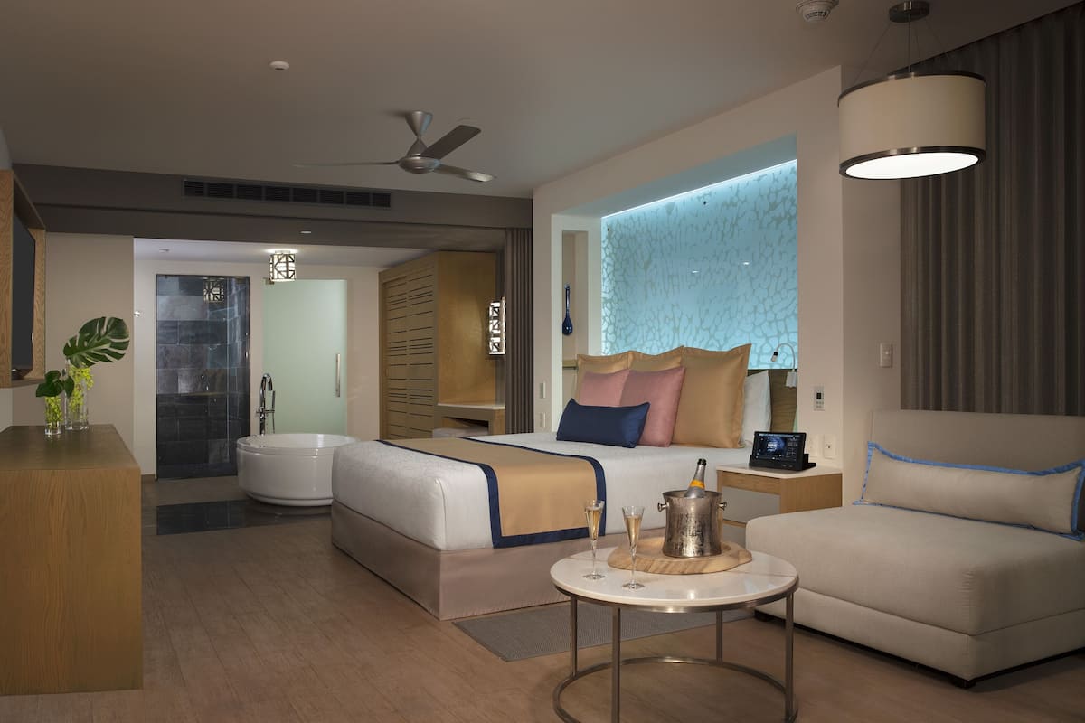 Une chambre d’hôtel moderne équipée d’un lit, d’un canapé, d’une table de chevet et d’une petite table avec des verres.