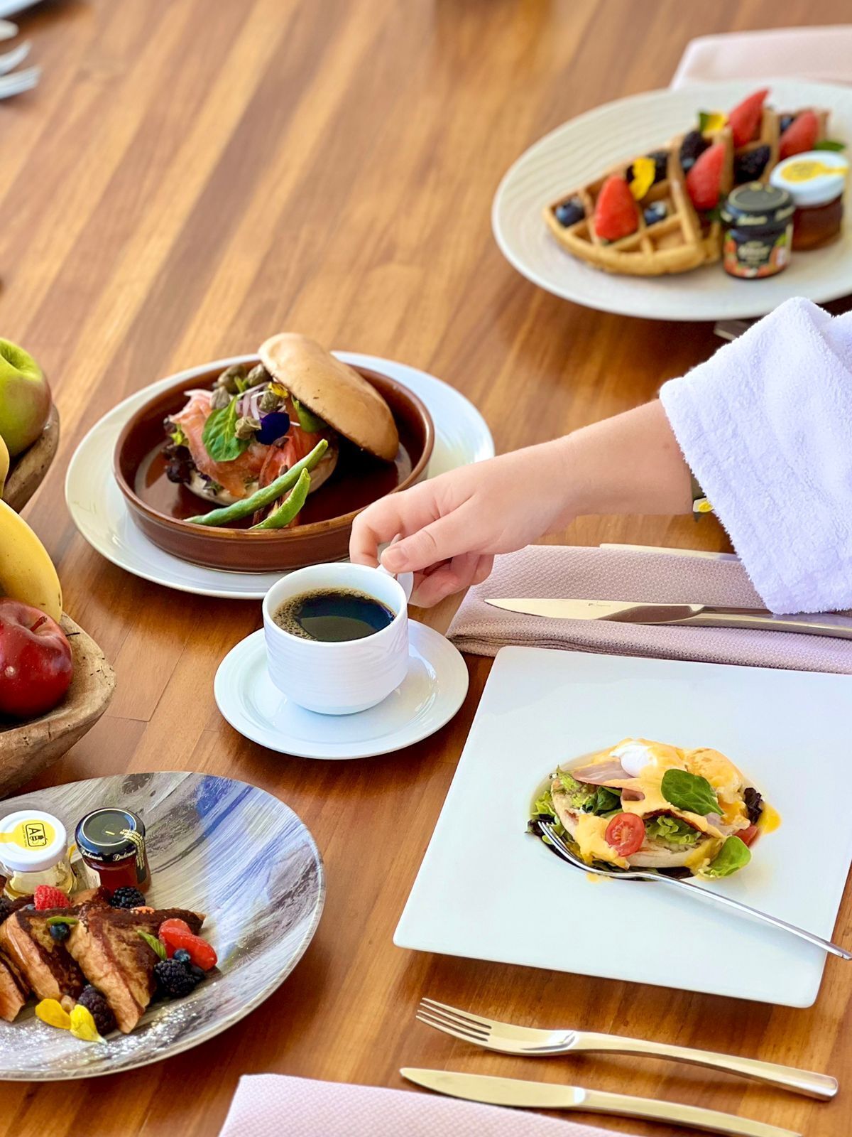 A dining table with various dishes, including waffles, a salad, and a cup of coffee.