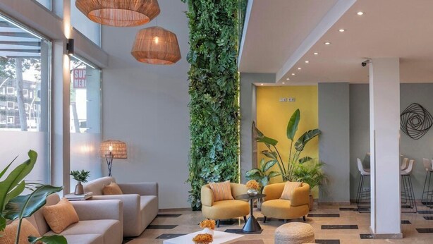 A modern lobby with a sofa set, a coffee table, and a vertical garden. - Hotel Serhs Del Port (Barcelona)
