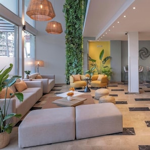 A modern lobby with a sofa set, a coffee table, and a vertical garden. - Hotel Serhs Del Port (Barcelona)