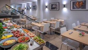 A buffet area with various food options, including salads, meats, and appetizers. There are multiple dining tables and chairs arranged in the room. - Hotel Serhs Del Port (Barcelona)