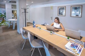 A modern office with a long table, chairs, laptops, and framed pictures on the wall. - Hotel Serhs Del Port (Barcelona)