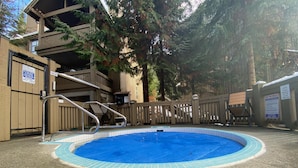 Una piscina con muelle de madera, escalera metálica y zona delimitada por una valla.
