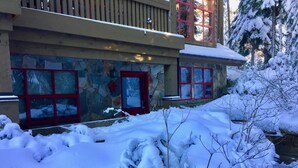 Un edificio de piedra con ventanas de marco rojo y un paisaje cubierto de nieve.