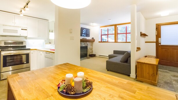 Una cocina moderna con electrodomésticos de acero inoxidable, un comedor con mesa de madera y una sala de estar acogedora con chimenea.
