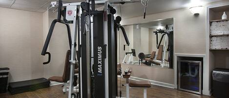 Une salle de sport équipée d'un appareil MAXIMUS, dotée d'un murmiroir et d'un plancher en bois.
