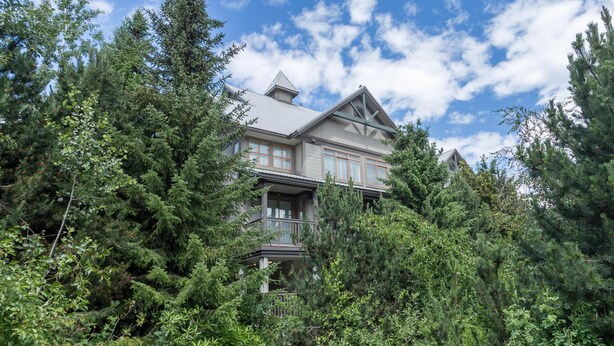A large, two-story house surrounded by dense forest. - Bright and Clean, Walk Everywhere, Shared Pool and Hot Tub (Whistler)