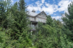 A large, two-story house surrounded by dense forest. - Bright and Clean, Walk Everywhere, Shared Pool and Hot Tub (Whistler)