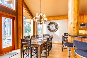A dining area with a wooden table and chairs, a chandelier, and a clock on the wall.