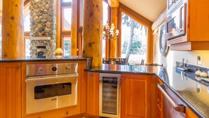 Une cuisine avec des meubles en bois, un mur en pierre et un four encastré.