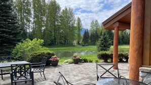 Une terrasse extérieure avec vue sur un terrain de golf, entourée d’arbres et de plantes en pot.