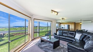 A spacious living room with a large window offering a view of the sea and a road. - With South Beach views, a relaxed family home (PORT FAIRY)