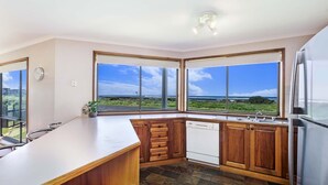 A kitchen with large windows, wooden cabinets, and a stainless steel refrigerator. - With South Beach views, a relaxed family home (PORT FAIRY)