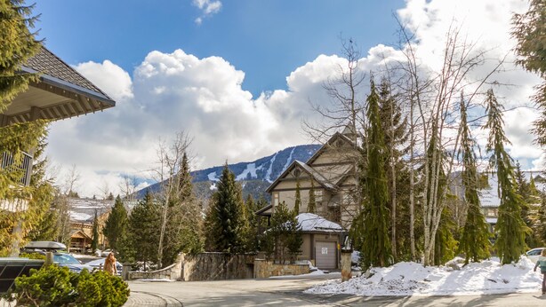 A mountain cabin with a stone wall, snow-covered ground, and a clear sky. - Fabulous Location Private Hot Tub, NO Car Needed, Sleeps 8 (Whistler)