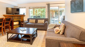 A living room with a fireplace, a sofa, a coffee table, and a television. - Fabulous Location Private Hot Tub, NO Car Needed, Sleeps 8 (Whistler)