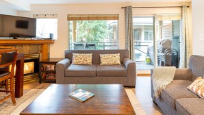 A living room with a fireplace, a sofa, a coffee table, and a television. - Fabulous Location Private Hot Tub, NO Car Needed, Sleeps 8 (Whistler)