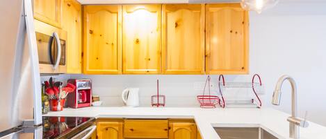 A modern kitchen with wooden cabinets, stainless steel appliances, and a white countertop.