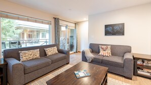 A modern living room with two grey sofas, a wooden coffee table, and a bookshelf. - Fabulous Location Private Hot Tub, NO Car Needed, Sleeps 8 (Whistler)