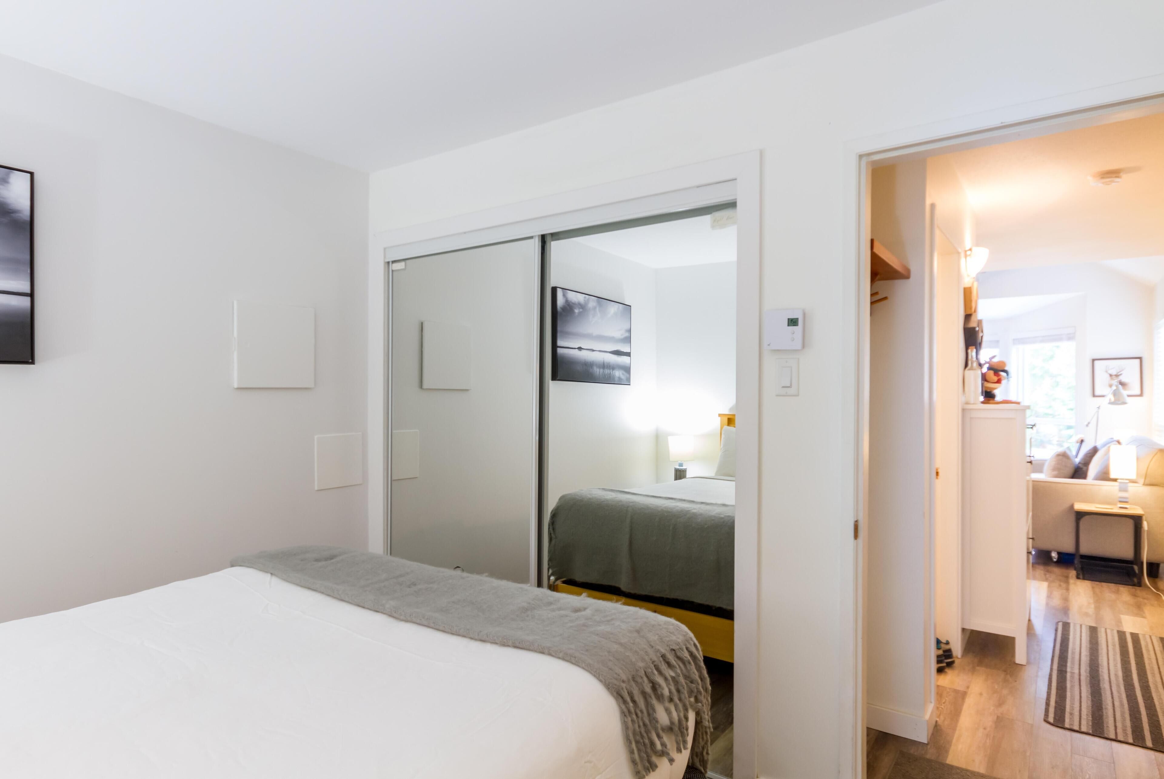 A bedroom with a bed, a wardrobe, and a mirror.