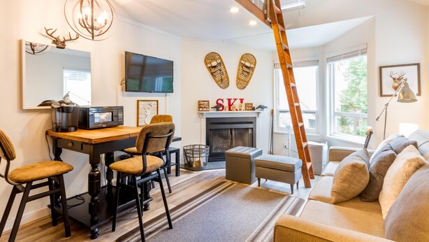A modern living room with a fireplace, a television, and a dining area with a wooden table and chairs.