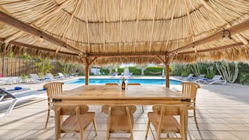 Relax by the pool with a meal at this outdoor dining area, featuring a pool surrounded by lounge chairs and umbrellas.