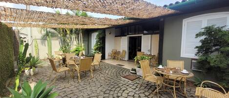 Un patio con suelo de piedra, muebles de mimbre y plantas en macetas.