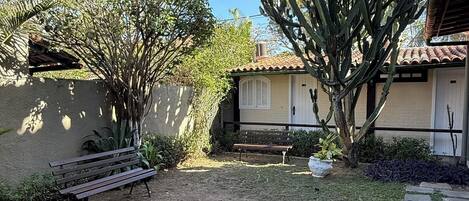 A garden with a cactus, a bench, and a building with a tiled roof.