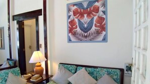 Una habitación con un conjunto de sofá, una lámpara y dos cuadros con motivos florales en la pared.