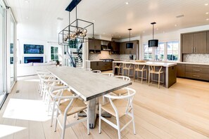 A modern kitchen with a central island, wooden flooring, and a staircase leading to an upper level. - Exquisite Custom Home in the Heart of East Hampton (East Hampton)