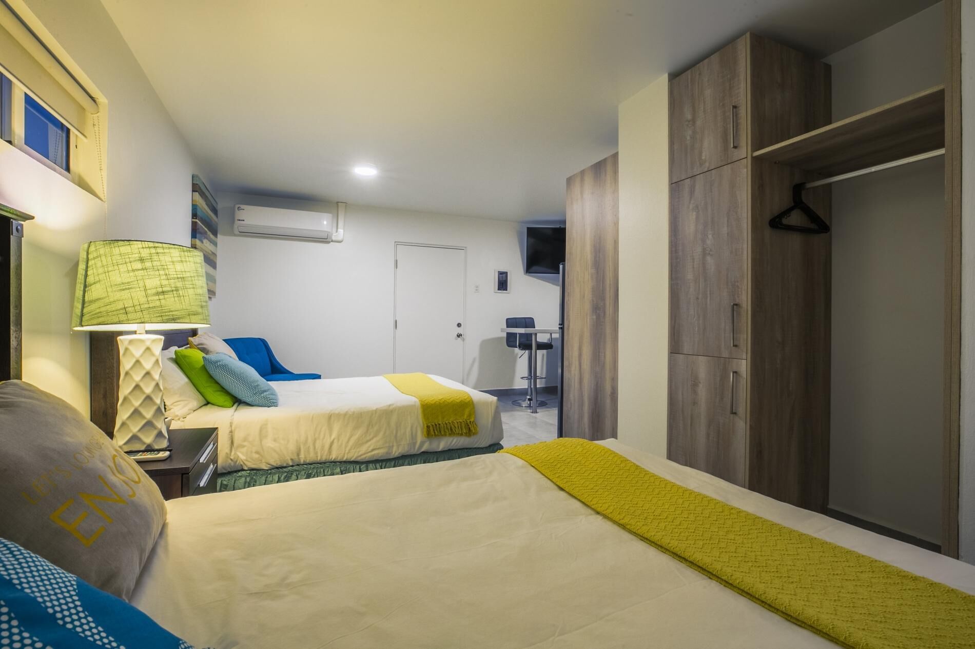 Ett hotellrum med två sängar, ett skrivbord, en stol, en garderob och en tv.