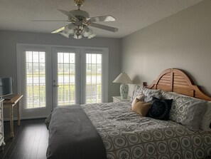 Relax in this serene bedroom with a large bed, ceiling fan, and comfortable seating area.