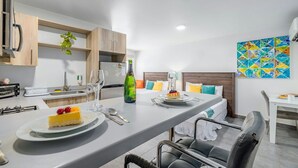 Een moderne keuken met een eetgedeelte, een koelkast, een magnetron, een spoelbak en een tafel gedekt voor twee personen, inclusief dessert.