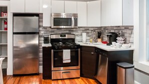 A modern kitchen with stainless steel appliances, wooden flooring, and white cabinetry. - Gorgeous Wooster Sq. apt. - wshr/dryr, parking (New Haven)