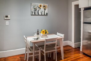 Comedor con una mesa dispuesta para cuatro personas, un cuadro sobre la mesa y un refrigerador a la derecha.