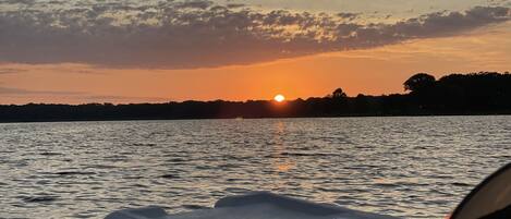 Ein Sonnenuntergang über dem Wasser, im Vordergrund ein Boot.
