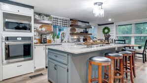 Een moderne keuken met een groot schiereiland, barkrukken en inbouwapparatuur.