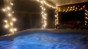 Ett bubbelbad omgivet av ljusslingor, träväggar och ett takförsett utomhusområde.
