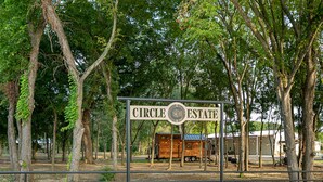 A sign for Circle Estate with a rustic wooden structure and a fenced area. - Circle C Cabin Perfect for Cozy Relaxing Retreats (Caldwell)