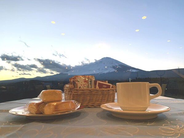 A table with a plate of pastries and a cup on a tablecloth, with a wicker basket and a key visible. - Fuji Mihana Resort (Oyama)