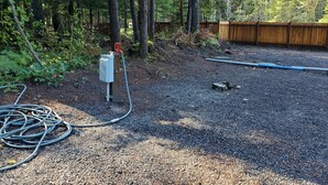 A gravel driveway with a hose and a wooden post. - RV Flat Lot- Tatoosh Timbers - No Bedroom or Bathroom RV Lot only.  (Packwood)