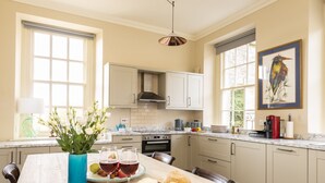 A kitchen with a marble countertop, white cabinets, and a large window. - The Courtyard House, Dorchester (Dorchester)