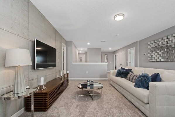 A modern living room with a flat-screen TV, a coffee table, a sofa, and a decorative wall.