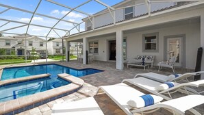 A swimming pool with lounge chairs, a covered patio, and a view of other buildings. - Ultimate New 8 Bedroom 5 Bathroom Champions Gate Resort Property with Spa and Pool (Davenport)