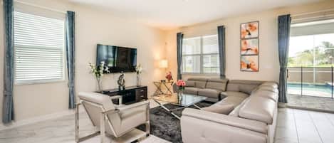 A living room with a sectional sofa, a TV, a coffee table, and a TV stand.