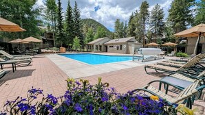 A pool area with lounge chairs and umbrellas, surrounded by trees and a mountain backdrop. - Quiet Condo w/Wood Fireplace Near Trails (Keystone)