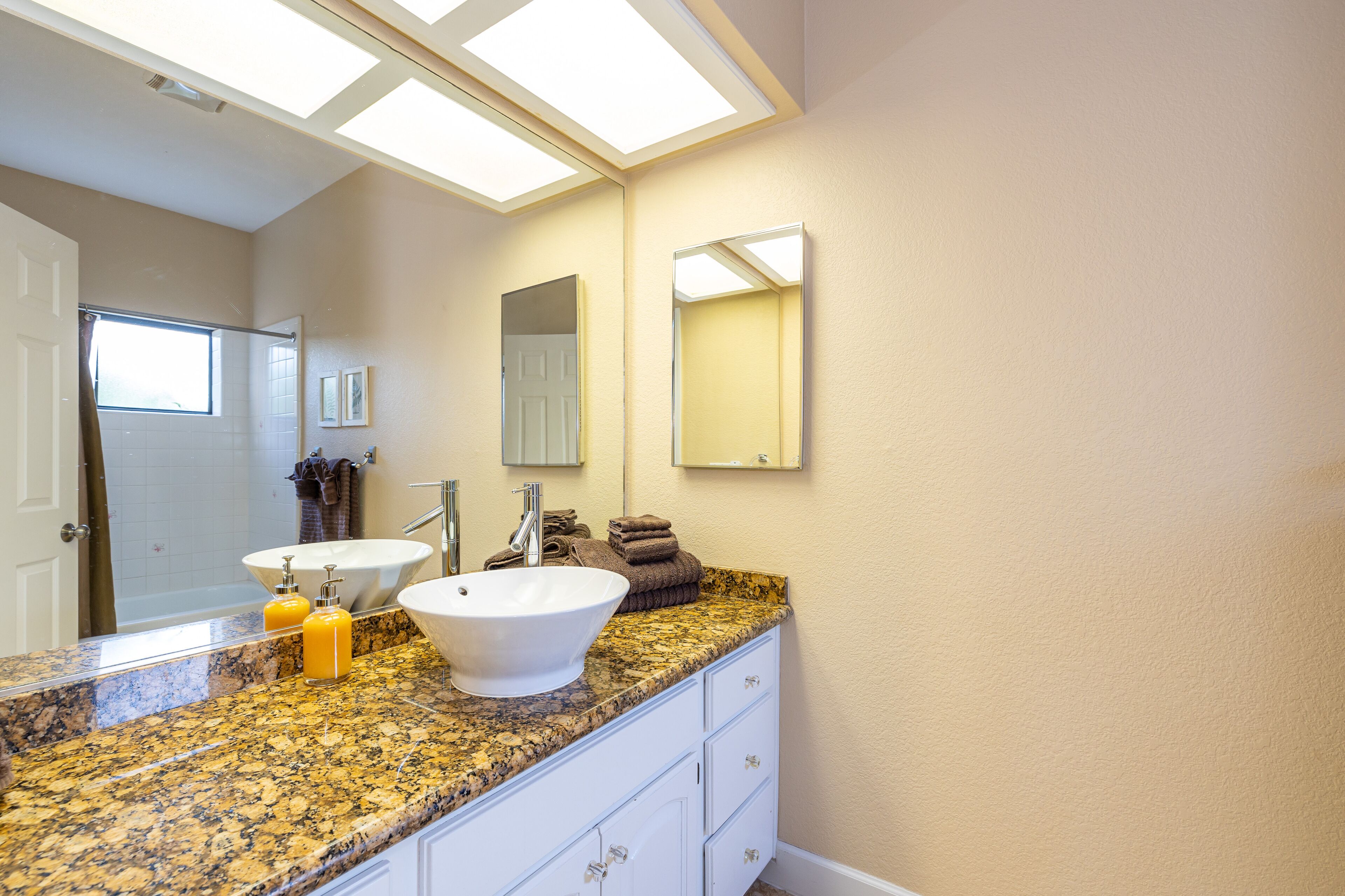A bathroom with two sinks, a large mirror, and a window.