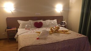 Una habitación de hotel con una cama, una mesita de noche y una lámpara fijada a la pared.